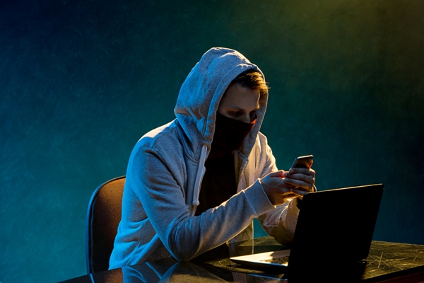 Hombre intentando estafar con teléfono y laptop