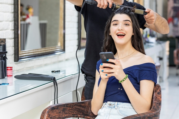 Peluquerías - Mujer feliz mientras le cortan y hacen rizados en el cabello