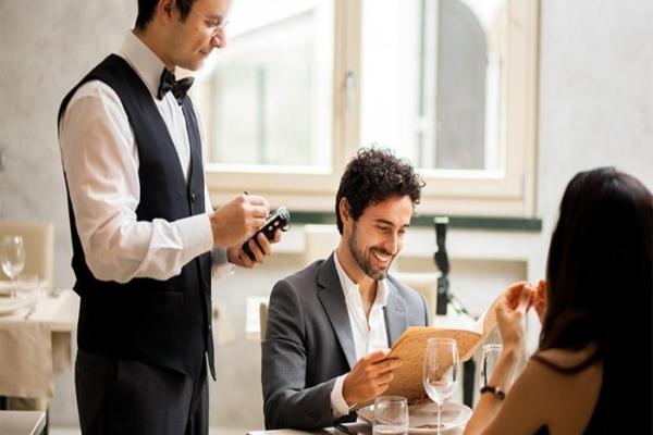 Camarero atendiendo el pedido de una pareja en un restaurante de Madrid