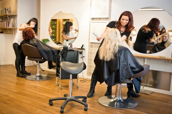 Estilistas haciendo un corte y alisado de cabello a influencers, en un salón de peluquería moderno y elegante
