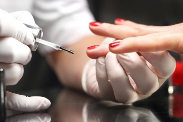 Manicura en Madrid - Manicurista pintando las uñas de una mujer de color rojo