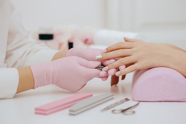 Manicura en Madrid - Manicurista arreglando las uñas de una mujer, cortándolas y pintándolas