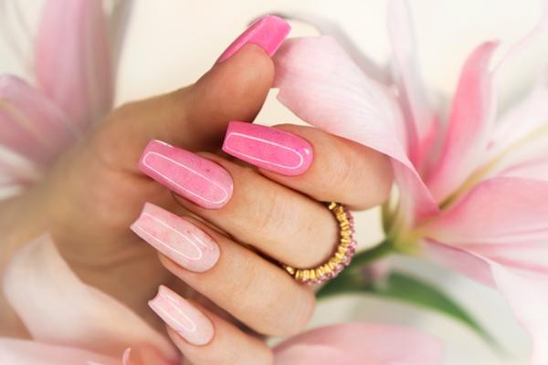 Mujer mostrando sus extensiones de uñas con excelente cuidado y trabajo de pintura, en color rosa degradado