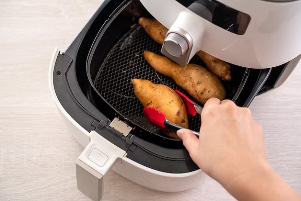 Freidora de aire - Persona sacando de la canasta de la freidora los alimentos que ya están cocinados