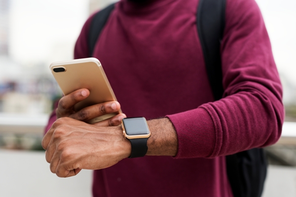 Hombre sincronizando su smartwatch con el smartphone compatible, para tener acceso a todas las funciones
