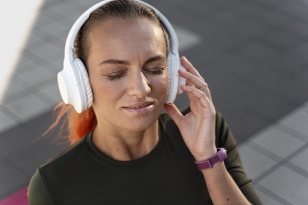 Mujer escuchando música a alto volumen con sus audífonos Bluetooth mientras hace ejercicio