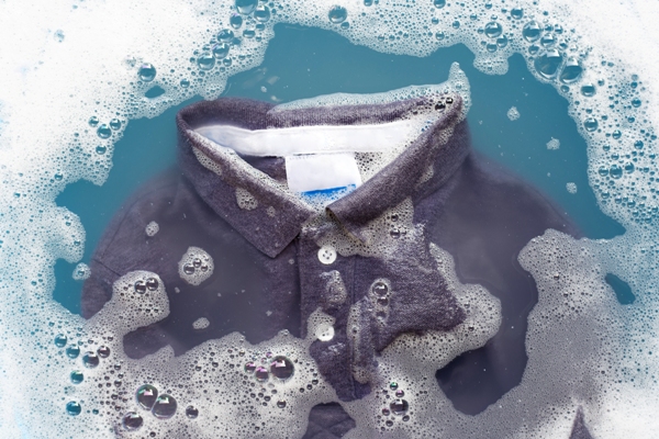 Camisa negra en remojo para eliminar todos los residuos y así se pueda fijar mejor el color al teñirla