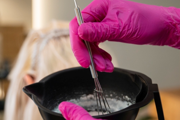Tinte para ropa - Mujer preparando la mezcla del tinte, para luego colocarla en el recipiente donde va a teñir las prendas