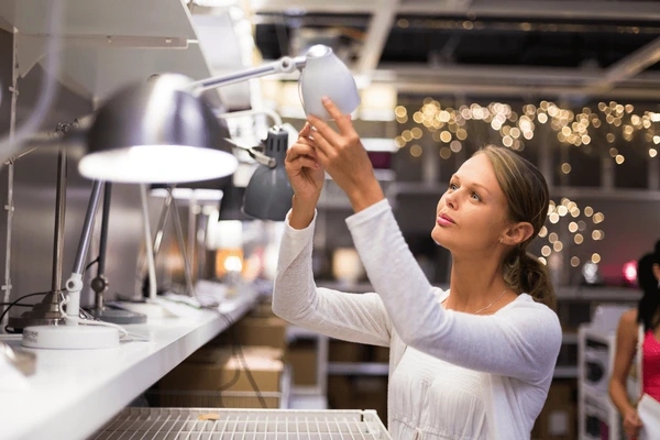 Mujer observando varios modelos de lámparas, para escoger la que más combine con su estilo y decoración