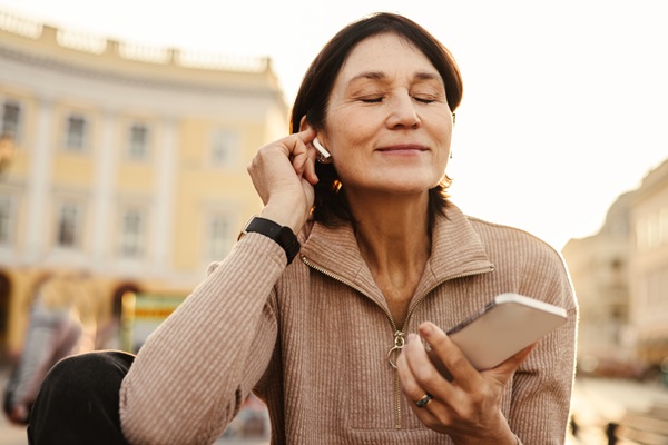 Auriculares inalámbricos - Mujer escuchando música desde su teléfono por Bluetooth con unos audífonos inalámbricos