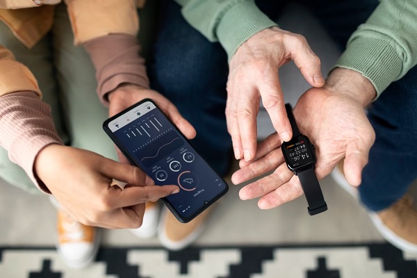 Reloj inteligente - Persona explicándole a otra como sincronizar la información deportiva y de salud entre el smartphone y el smartwatch