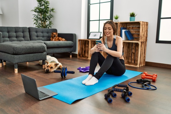 Mujer preparándose para realizar ejercicios desde casa, con todos los materiales deportivos necesarios, como pesas, esterilla, bandas elásticas y cuerda de saltar