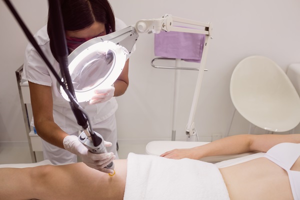 Doctora eliminando el vello corporal de una paciente femenina con tecnología de última generación