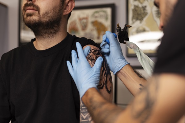Artista profesional realizando un tatuaje a un hombre en el brazo, con un diseño personalizado que marca una experiencia vivida