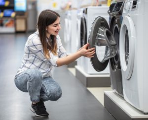 Cómo escoger una lavadora de ropa - mujer en un almacena de venta de electrodomésticos eligiendo una lavadora