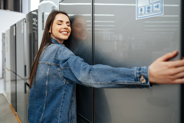 Mejores marcas de frigoríficos - Mujer abrazando un frigorífico de marca reconocida, el cual reúne todas las características que busca para su hogar