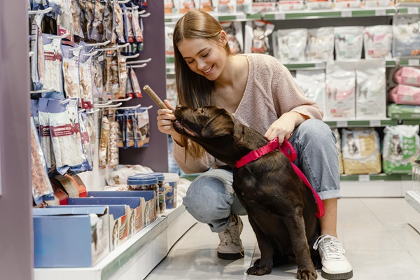 Mujer visitando una tienda para mascotas con su perro, con la finalidad de comprarle un juguete adecuado de buena calidad