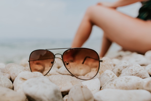 Comprar gafas de sol - Imagen de unas gafas de sol con lentes polarizados, puestas sobre las piedras de una playa