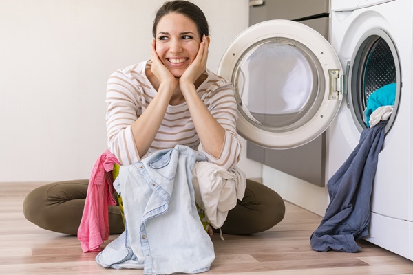 Escoger los electrodomésticos más eficientes - Mujer feliz al poder lavar todas sus prendas en un solo ciclo, ahorrando agua y energía