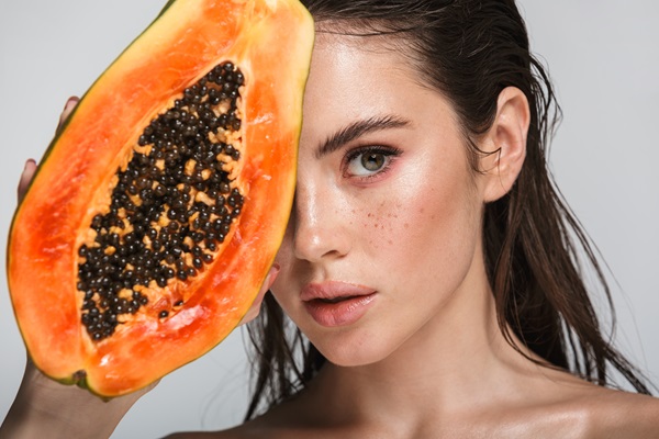 Mujer sosteniendo una papaya picada, la cual aporta una gran cantidad de vitaminas y minerales al cabello cuando se utiliza como mascarilla capilar