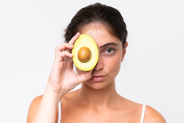 Productos naturales para el pelo - Mujer sosteniendo un aguacate picado, el cual aporta muchos beneficios como mascarilla capilar