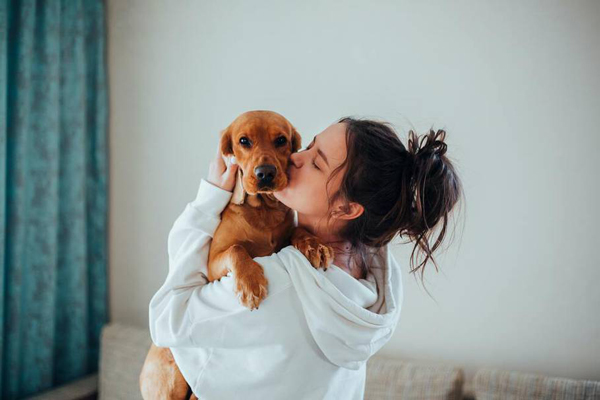 Hoteles pet friendly - Joven en bata de baño recién levantada carga y besa a su perro con mucho amor