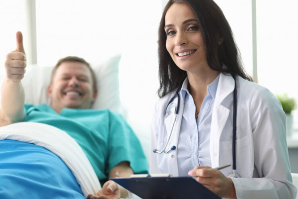 Gastroenterólogo en Madrid - Paciente en cama levanta el pulgar y se muestra satisfecho con la impecable atención de una doctora de dilatada experiencia