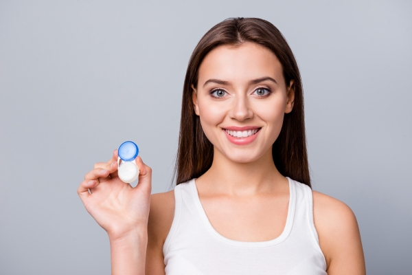 Lentillas progresivas - Mujer feliz sosteniendo un estuche de lentillas progresivas, las cuales ayudan a corregir la presbicia y otros problemas visuales