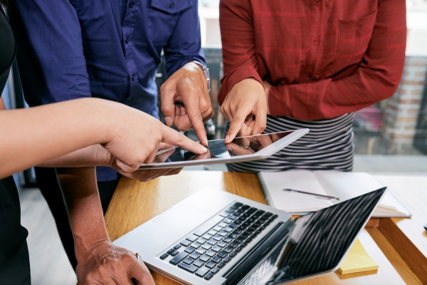 Equipo de trabajo utilizando una tableta y computadora para analizar la información de la organización