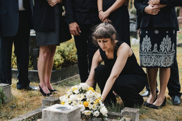 Familia en el entierro de un ser querido, colocando flores sobre la tumba para el último adiós