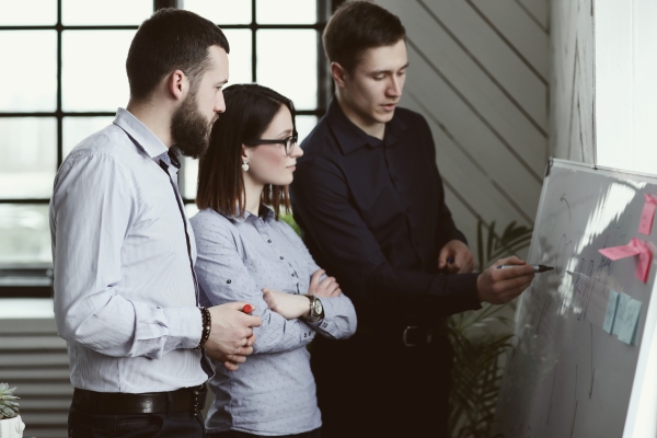 Equipo de trabajo utilizando una pizarra para analizar diferentes puntos de vistas y tomar decisiones