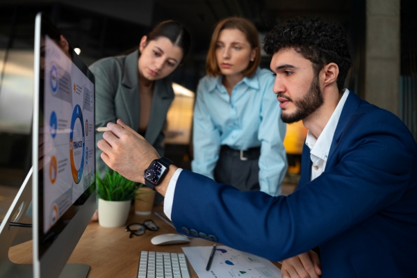 Empresa de servicios informáticos - Hombre explicando a 2 trabajadoras de la empresa una información importante, mediante un gráfico en la computadora