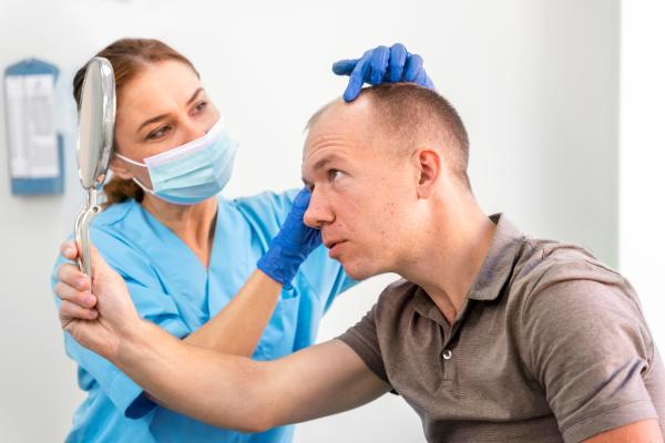 Médico especialista evaluando el cuero cabelludo de un paciente masculino, para determinar el mejor tratamiento capilar