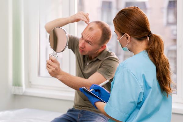 Médico especialista evaluando a un paciente masculino con alopecia, para determinar el tratamiento capilar más adecuado