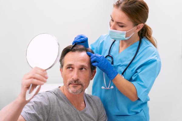 Mejores clínicas capilares en España - Médico especialista evaluando el cuero cabelludo de un paciente masculino, para diagnosticar las causas de la pérdida de pelo
