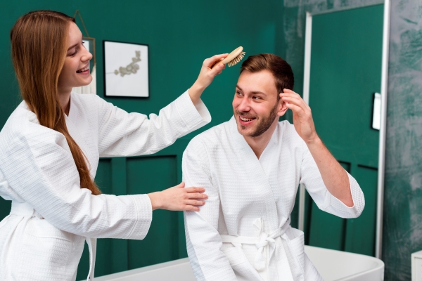 Mejores clínicas capilares en España - Mujer peinando de manera suave el cabello de un hombre, para mantener un cuidado capilar adecuado