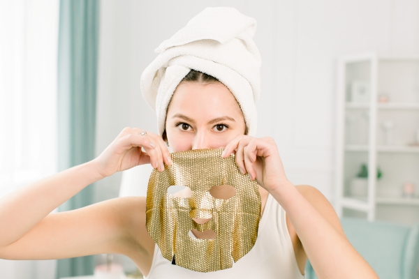 Exfoliante facial - Mujer sosteniendo una mascarilla facial, la cual ayuda a exfoliar el rostro y mantener una piel sana