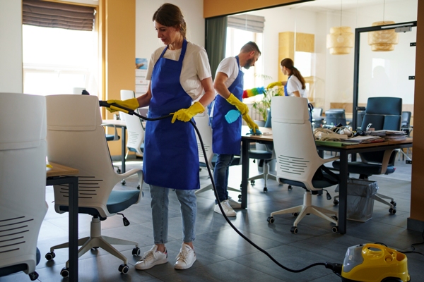 Empresa de servicio de limpieza - Trabajadora de limpieza utiliza una aspiradora para remover el polvo y la suciedad de las sillas de una oficina