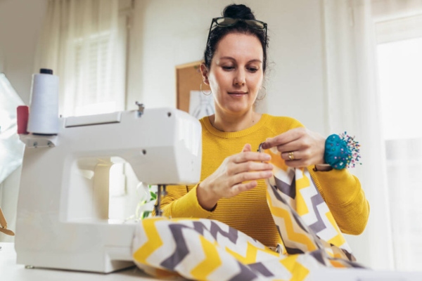 tiendas de arreglo de ropa - mujer sentada cosiendo con una maquina de coser