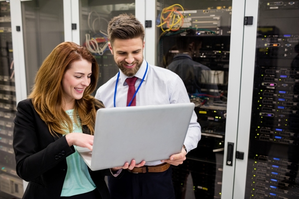 Empresa de servicios informáticos - Personas trabajando en la computadora de una empresa, al frente de unos servidores que almacenan toda la información