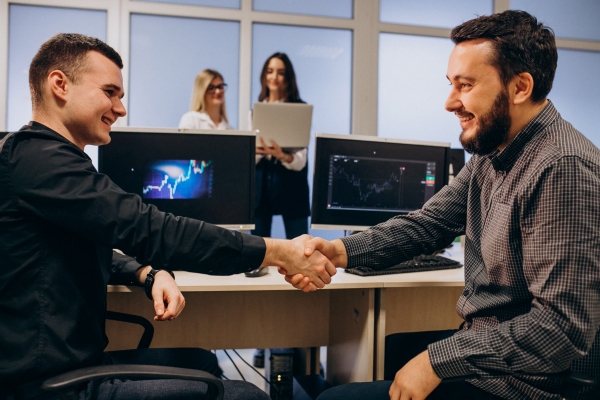 Empresa de servicios informáticos - 2 hombres estrechando sus manos en una empresa, como señal de haber conseguido un acuerdo beneficioso para ambos