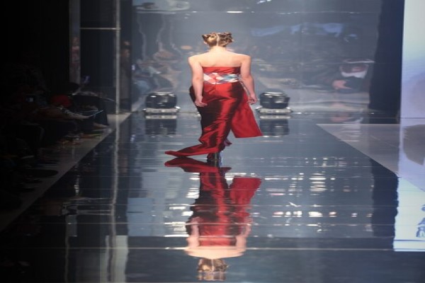 Colores en tendencia - Mujer modelando en una pasarela un vestido de color rojo radiante, lo que ofrece un look sostificado y elegante