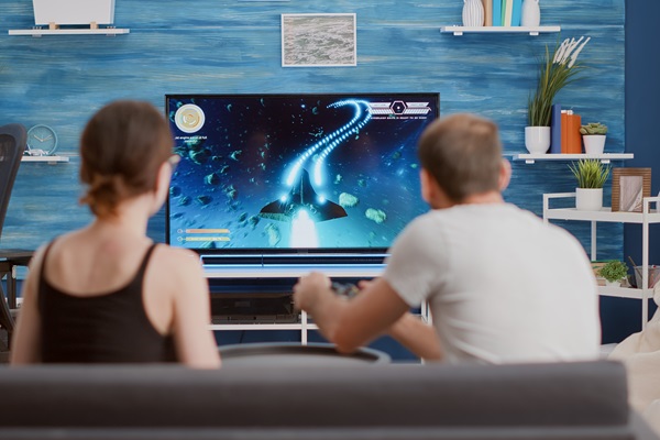 Pareja jugando videojuegos desde una consola, conectada a un televisor en la sala del hogar