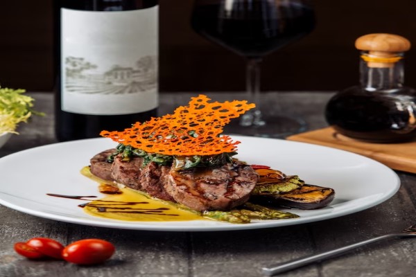 Propuestas gastronómicas 2024 - Presentación gourmet de un plato de carne aderezada con salsa y acompañada con verduras a la parrilla