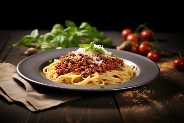 Propuestas gastronómicas 2024 - Presentación gourmet de un plato de pasta con carne molida y queso parmesano