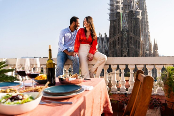 Ciudades gastronómicas de España - Pareja enamorada disfruta de una cena romántica en Barcelona con vista a la Sagrada Familia