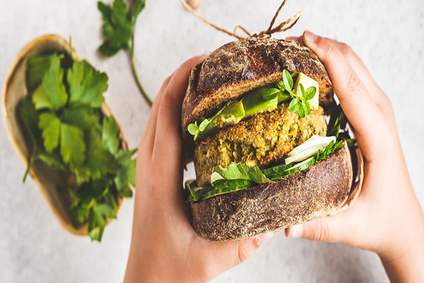Tendencias gastronómicas - Persona sujetando en sus manos una hamburguesa orgánica, hecha a base de plantas