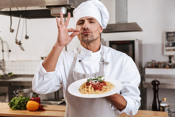 Restaurantes favoritos de los chefs - Cocinero haciendo un gesto de perfección muestra un plato de pasta en la cocina de un restaurante en Madrid