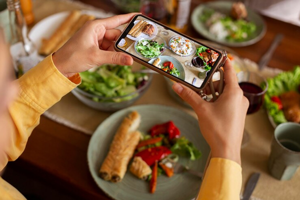 Tendencias gastronómicas - Persona sosteniendo su teléfono y tomando una foto a los platos de comida