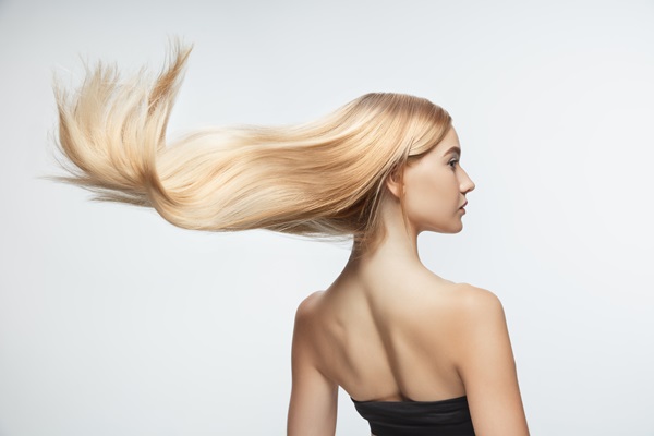Mujer posando con su cabello abundante, liso y radiante, gracias a un cuidado capilar adecuado